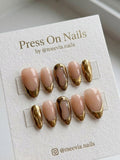 Almond-shaped nude press on nails with metallic gold French tips and 3D wavy nail art