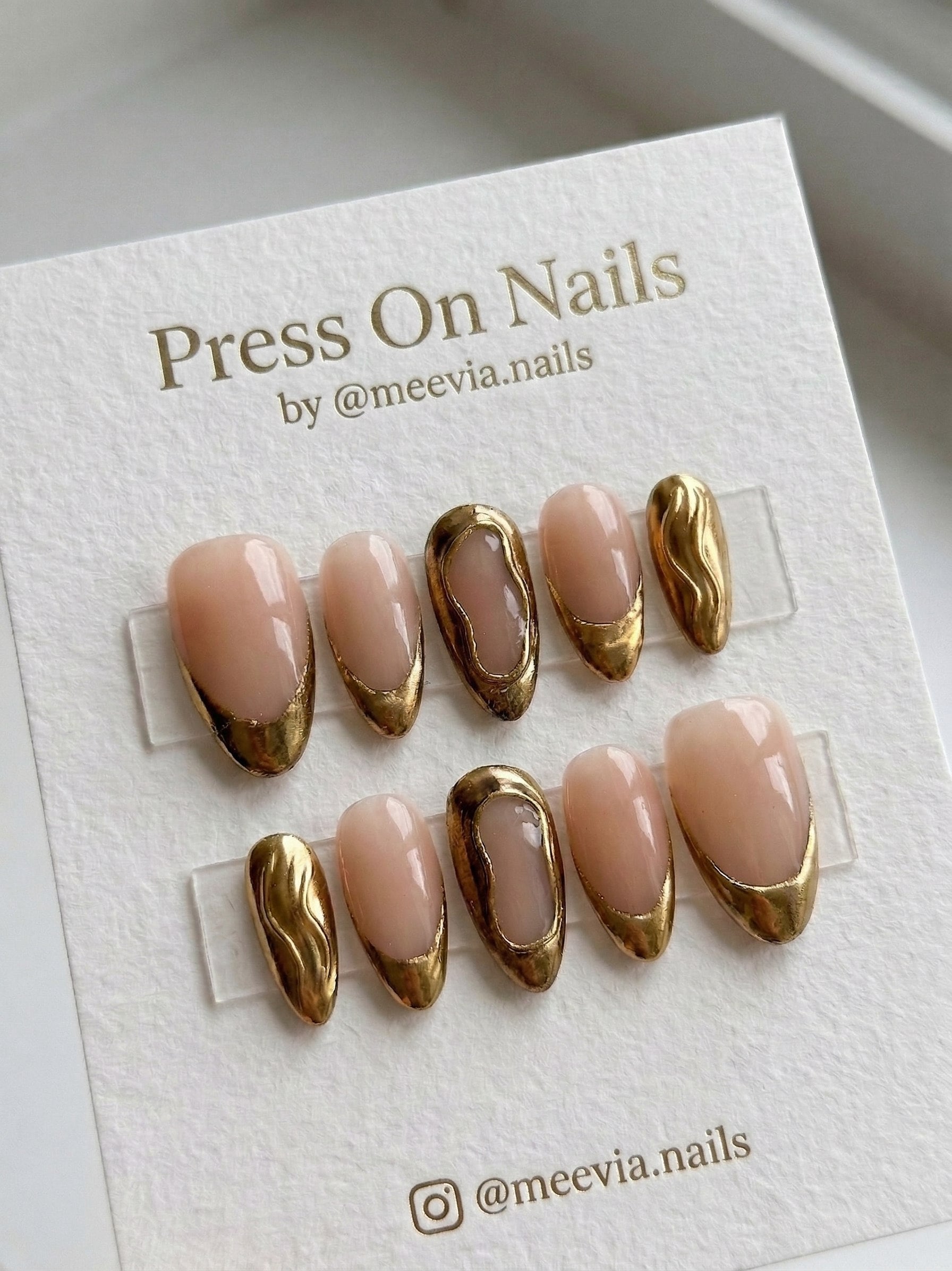 Almond-shaped nude press on nails with metallic gold French tips and 3D wavy nail art