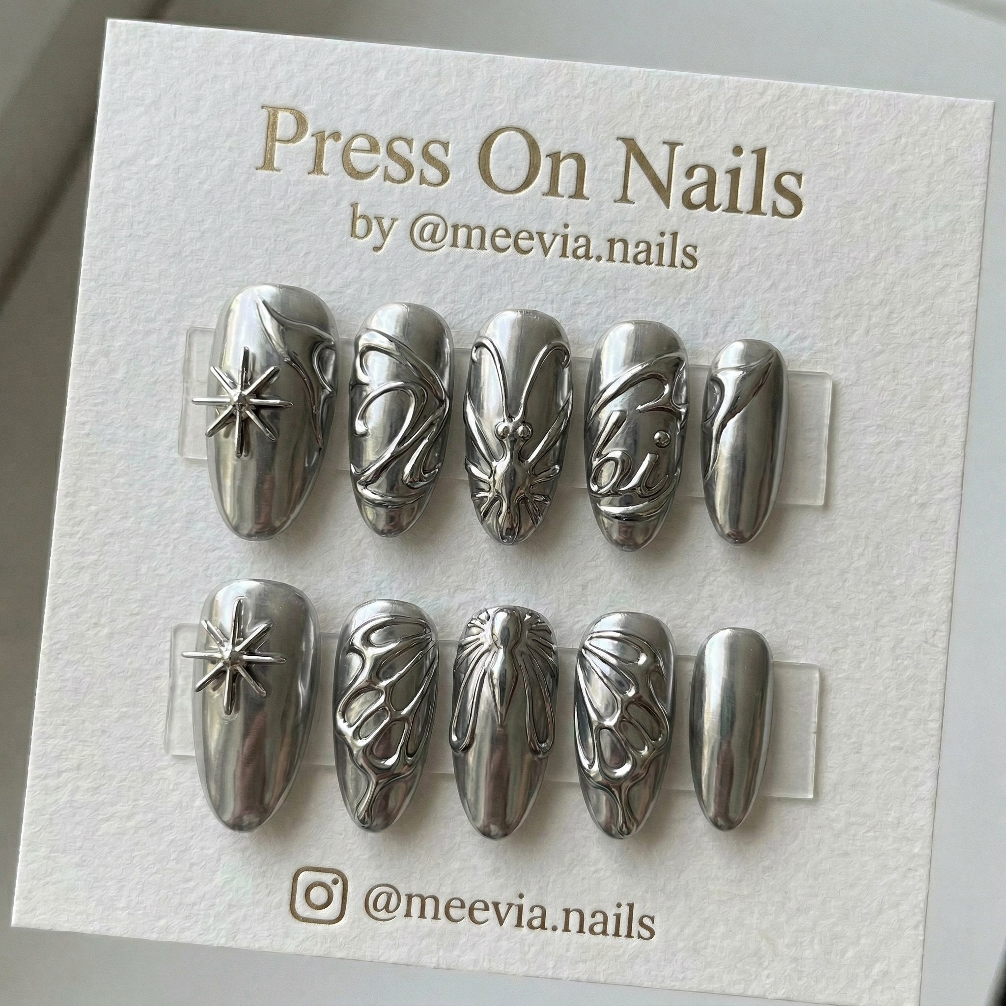Almond-shaped silver chrome press-on nails with 3D star and butterfly designs