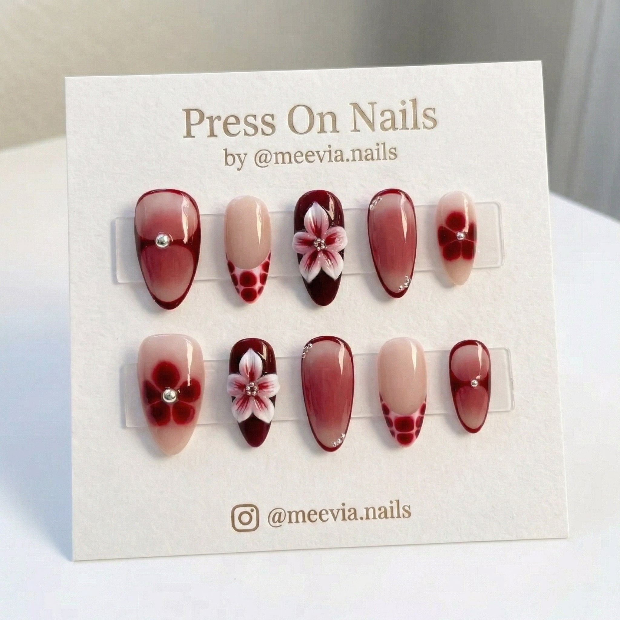 Almond-shaped red and nude press-on nails with 3D white flowers and French tip nail art