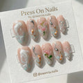 Almond-shaped press on nails featuring 3D koi fish and pink floral nail art on a nude base