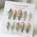 Stiletto-shaped press-on nail set featuring 3D dragonfly and floral nail art in sage green and pink
