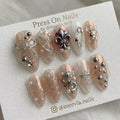 Almond-shaped glazed press-on nail set with 3D silver fleur-de-lis and bow embellishments