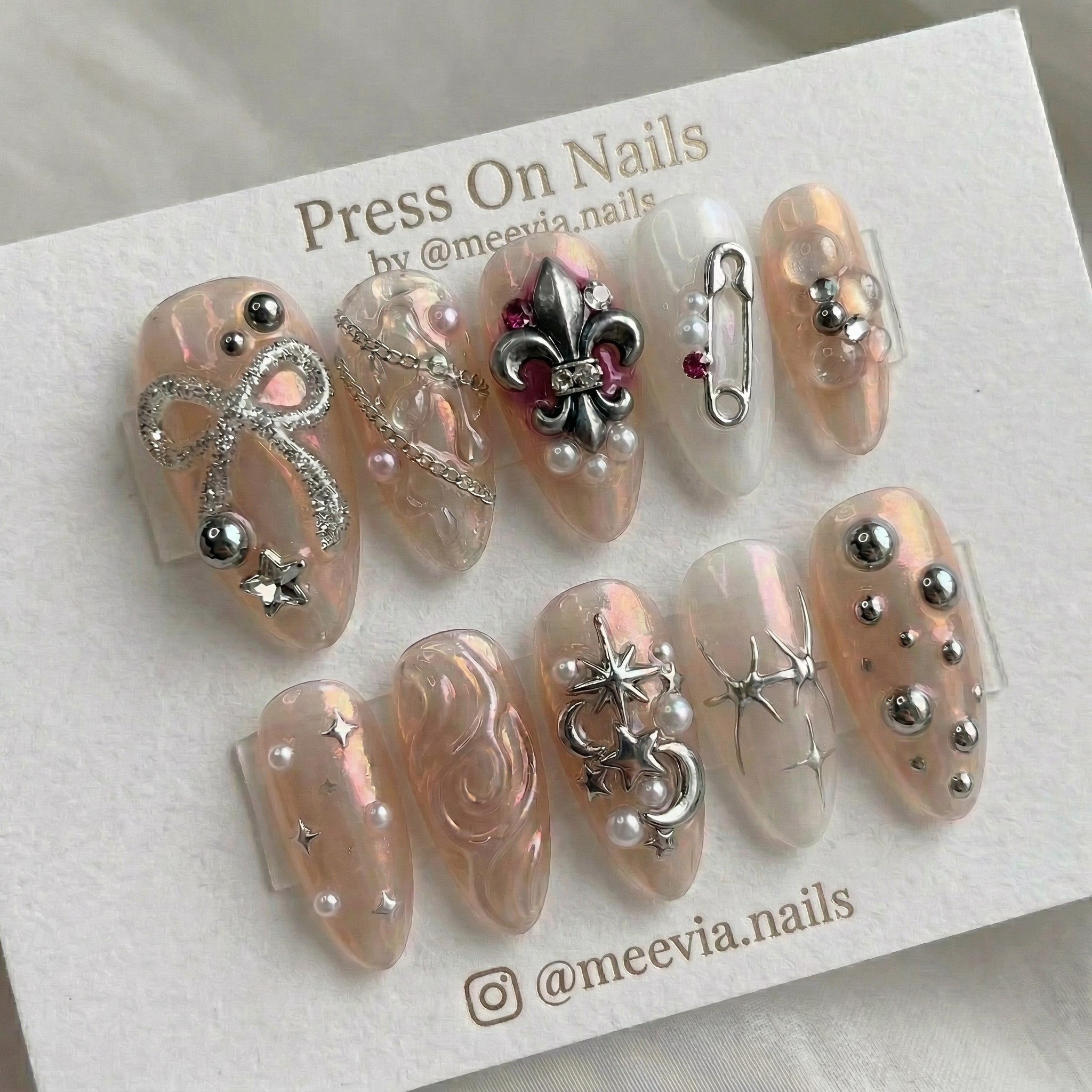 Almond-shaped glazed press-on nail set with 3D silver fleur-de-lis and bow embellishments