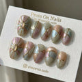 Almond-shaped iridescent press-on nails with 3D gold relief lines and shimmer finish