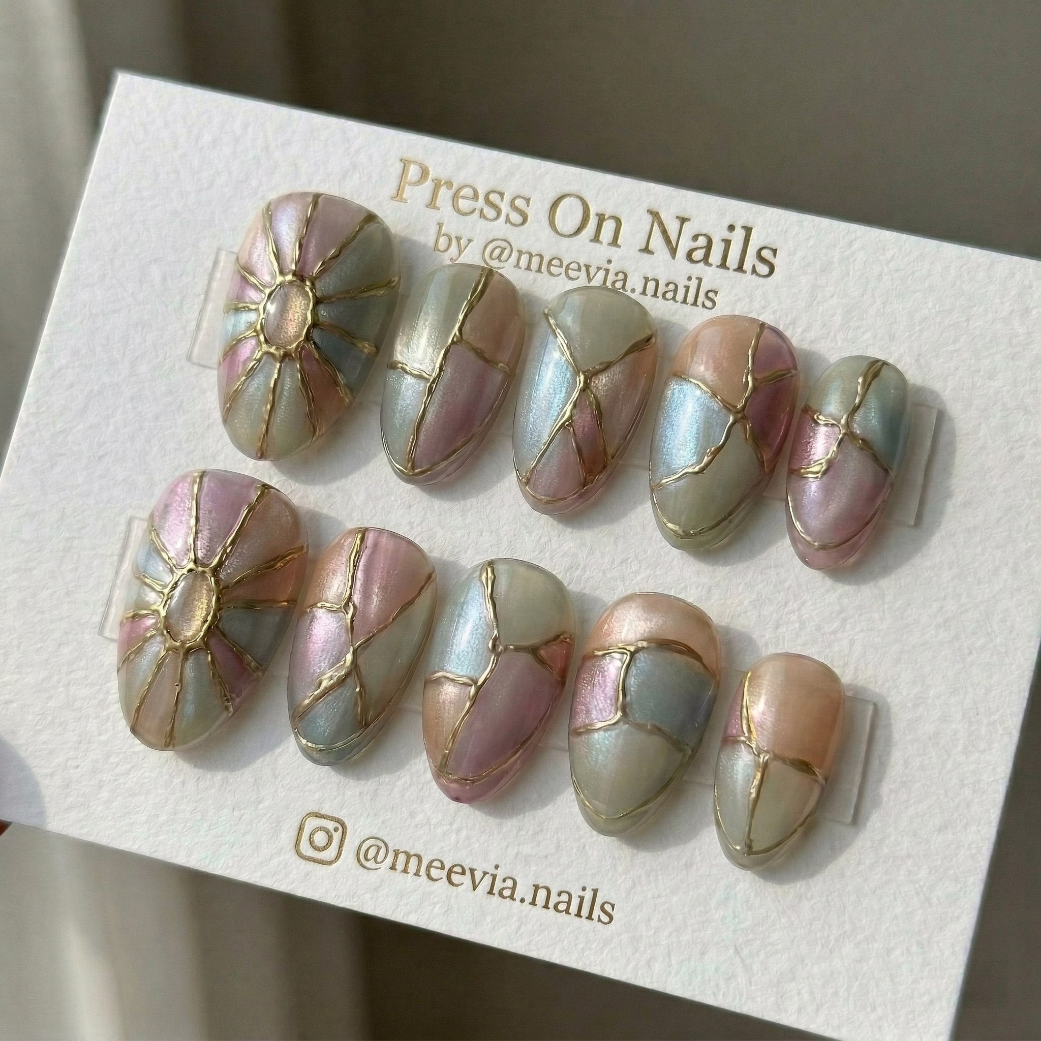 Almond-shaped iridescent press-on nails with 3D gold relief lines and shimmer finish