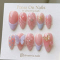 Almond-shaped pink press-on nails with 3D butterflies, floral art, and lavender French tips
