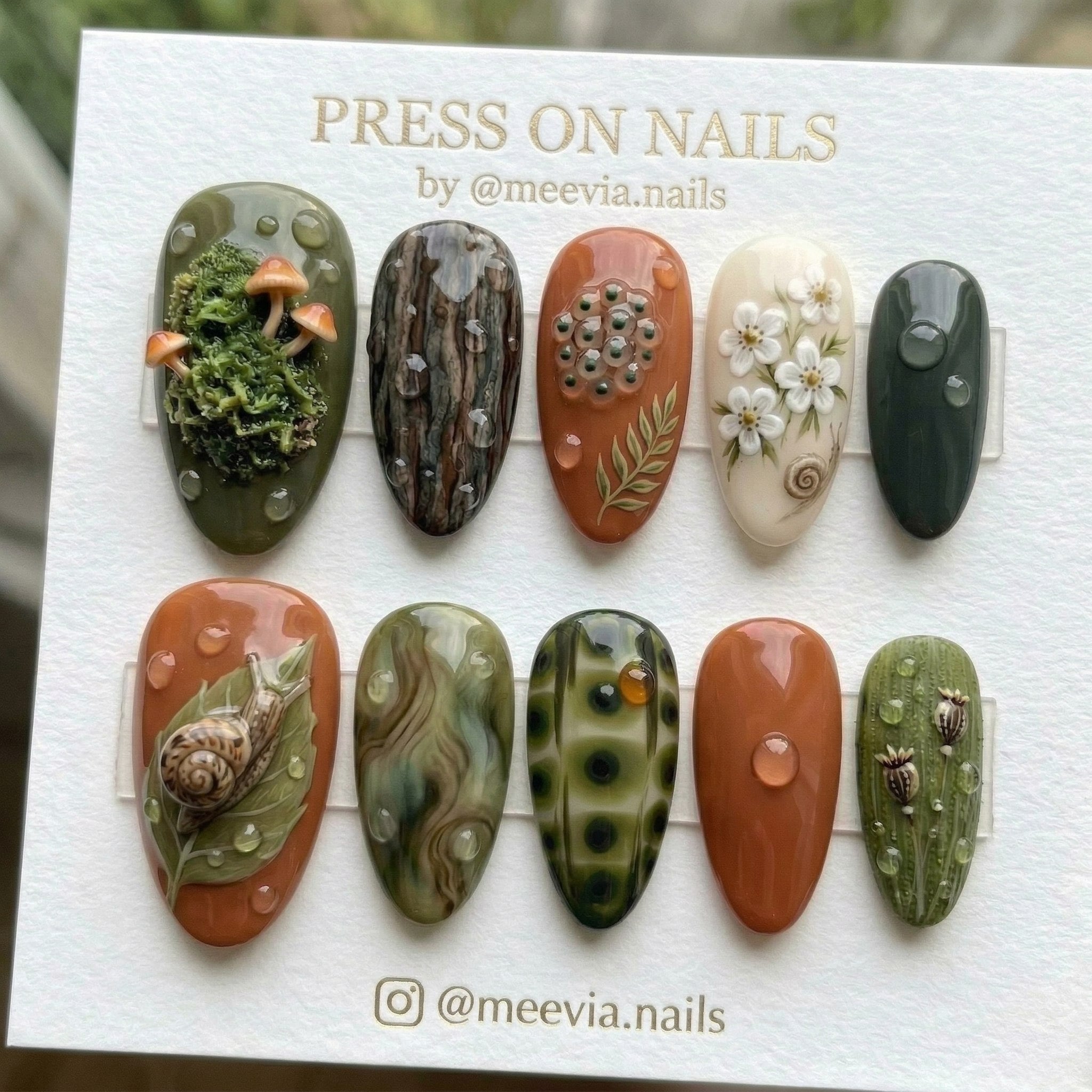 Almond-shaped forest-themed press-on nail set with 3D moss, mushrooms, and snail nail art.