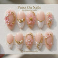 Almond-shaped pink press on nails with 3D floral art, gold vines, and pearls
