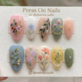Almond-shaped botanical floral press-on nails with 3D pearl and gold accents