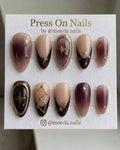 Almond-shaped celestial press-on nail set with burgundy French tips and 3D gold stars