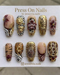 Long coffin-shaped press-on nail set featuring 3D roses, floral sketches, and metallic accents in green, burgundy, and white