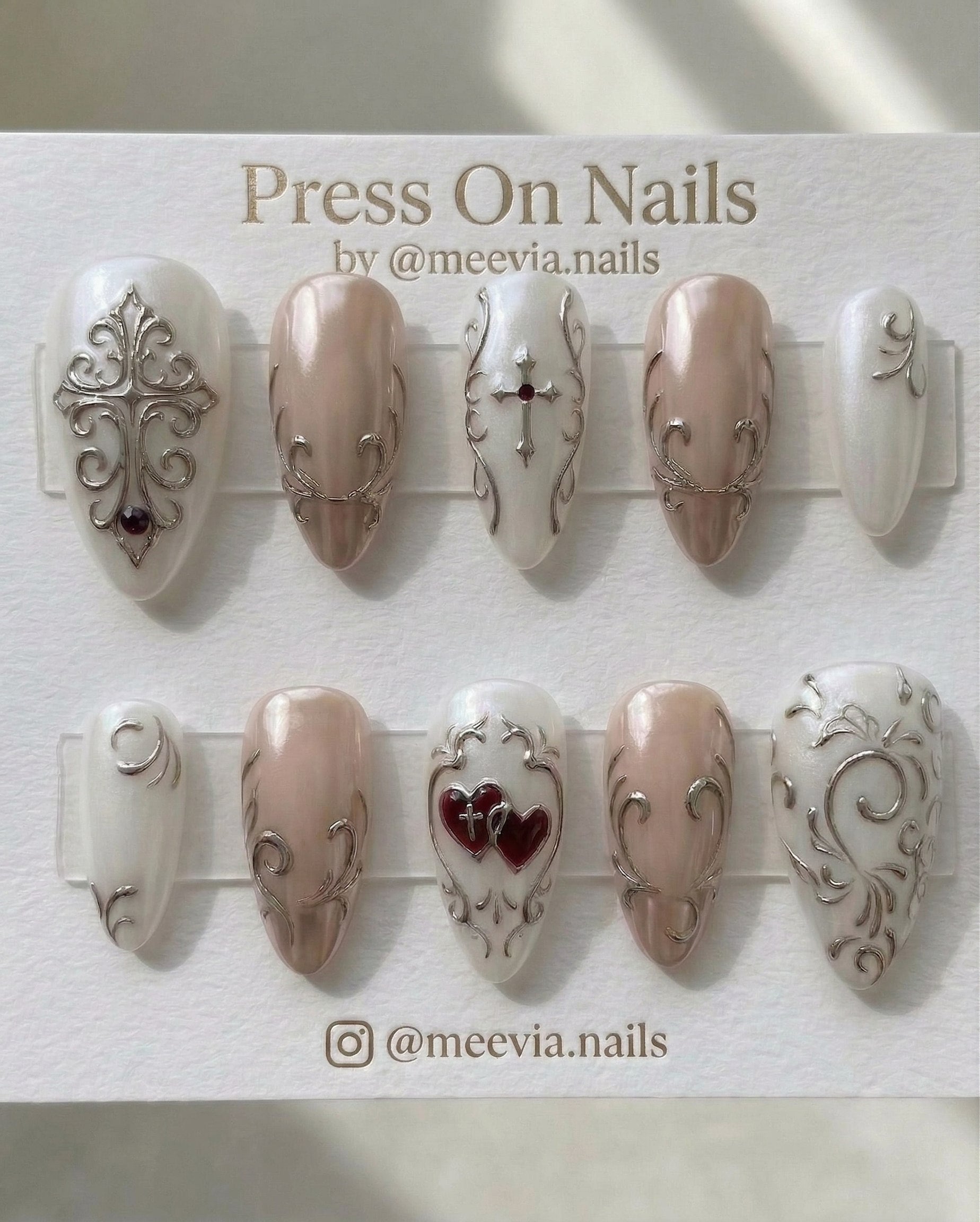 Almond-shaped gothic press-on nail set with silver 3D cross art and red heart accents.