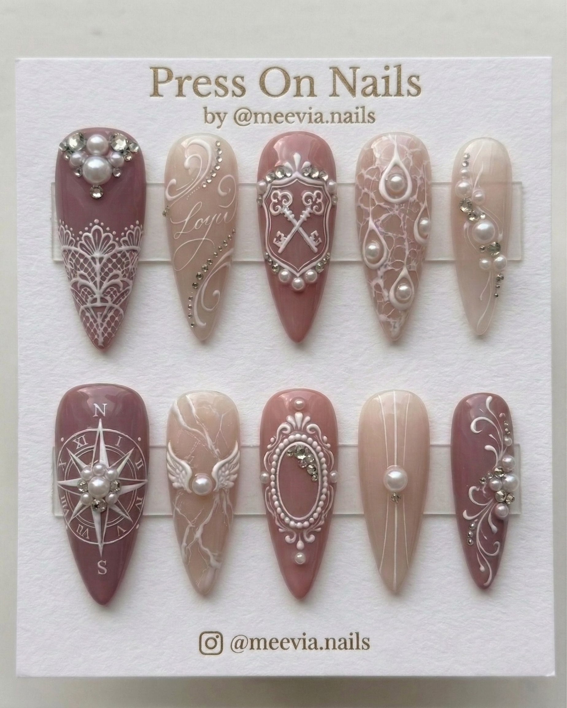 Stiletto-shaped mauve and beige press-on nails with 3D vintage keys, pearls, and lace nail art.