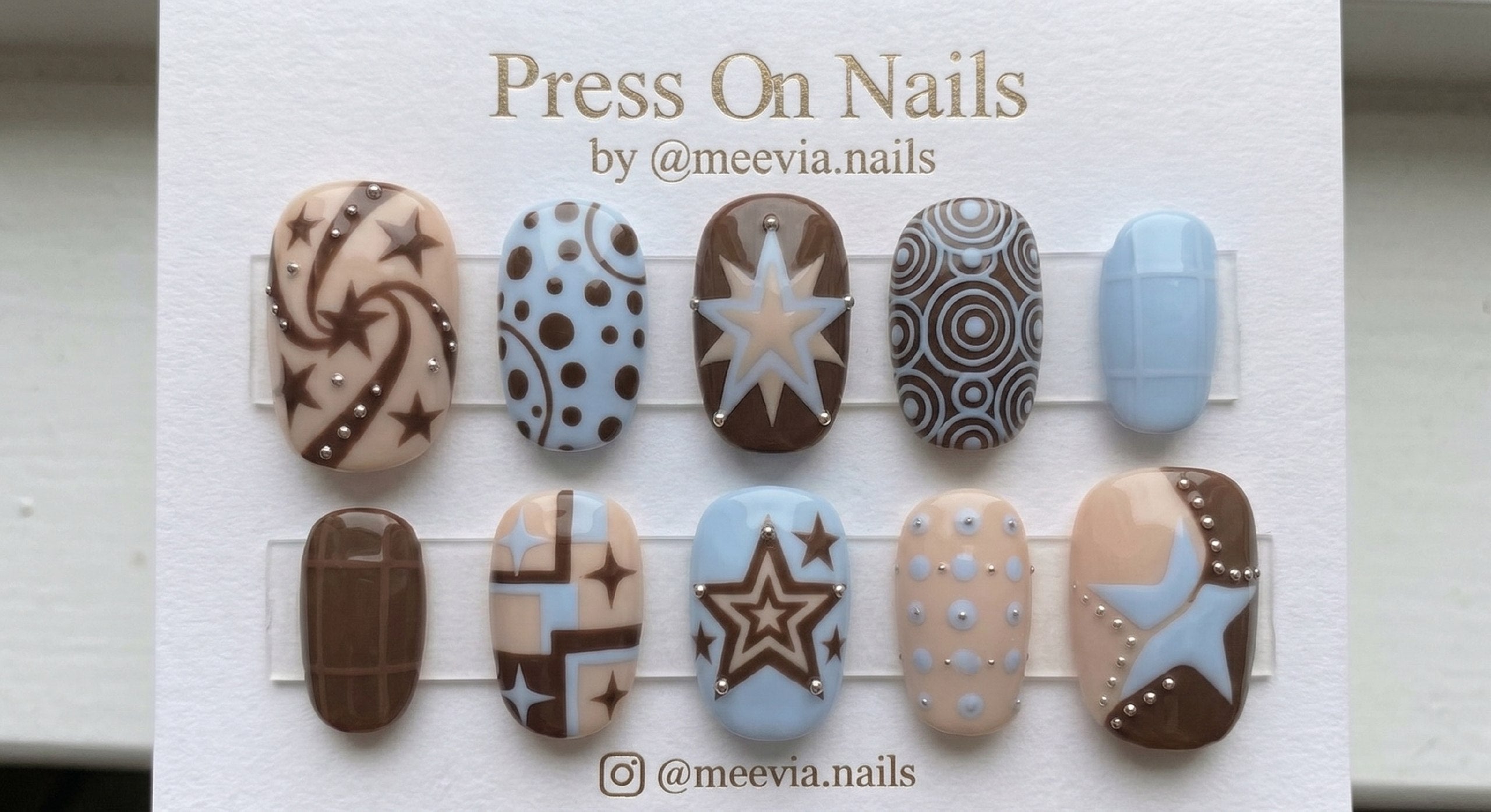 Oval-shaped brown and blue press-on nail set with star motifs and silver 3D beads
