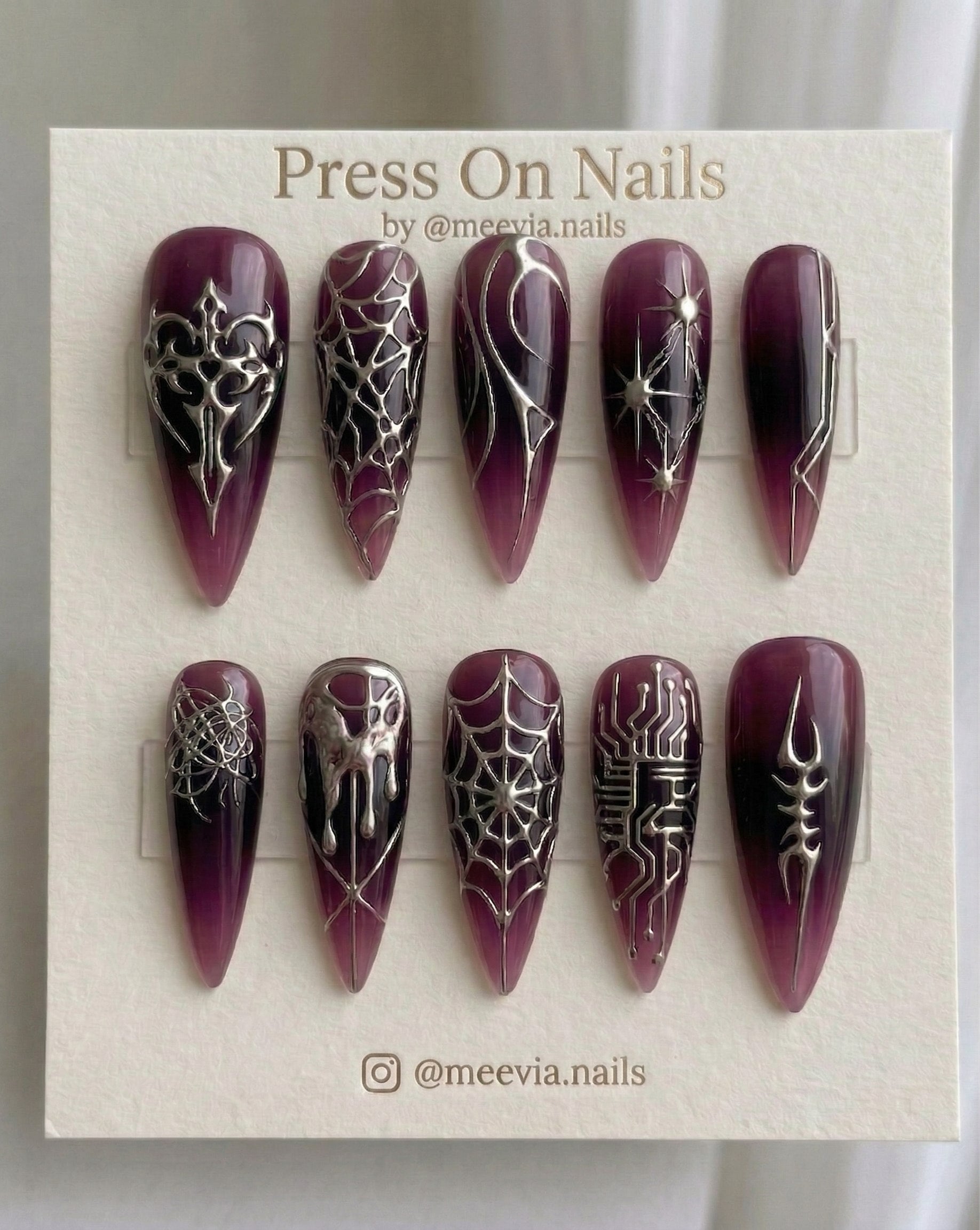 Long stiletto-shaped purple press-on nails with silver chrome gothic and cyber nail art designs