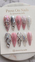 Stiletto-shaped pink press-on nail set with 3D silver metallic art, iridescent finishes, and crystal embellishments.
