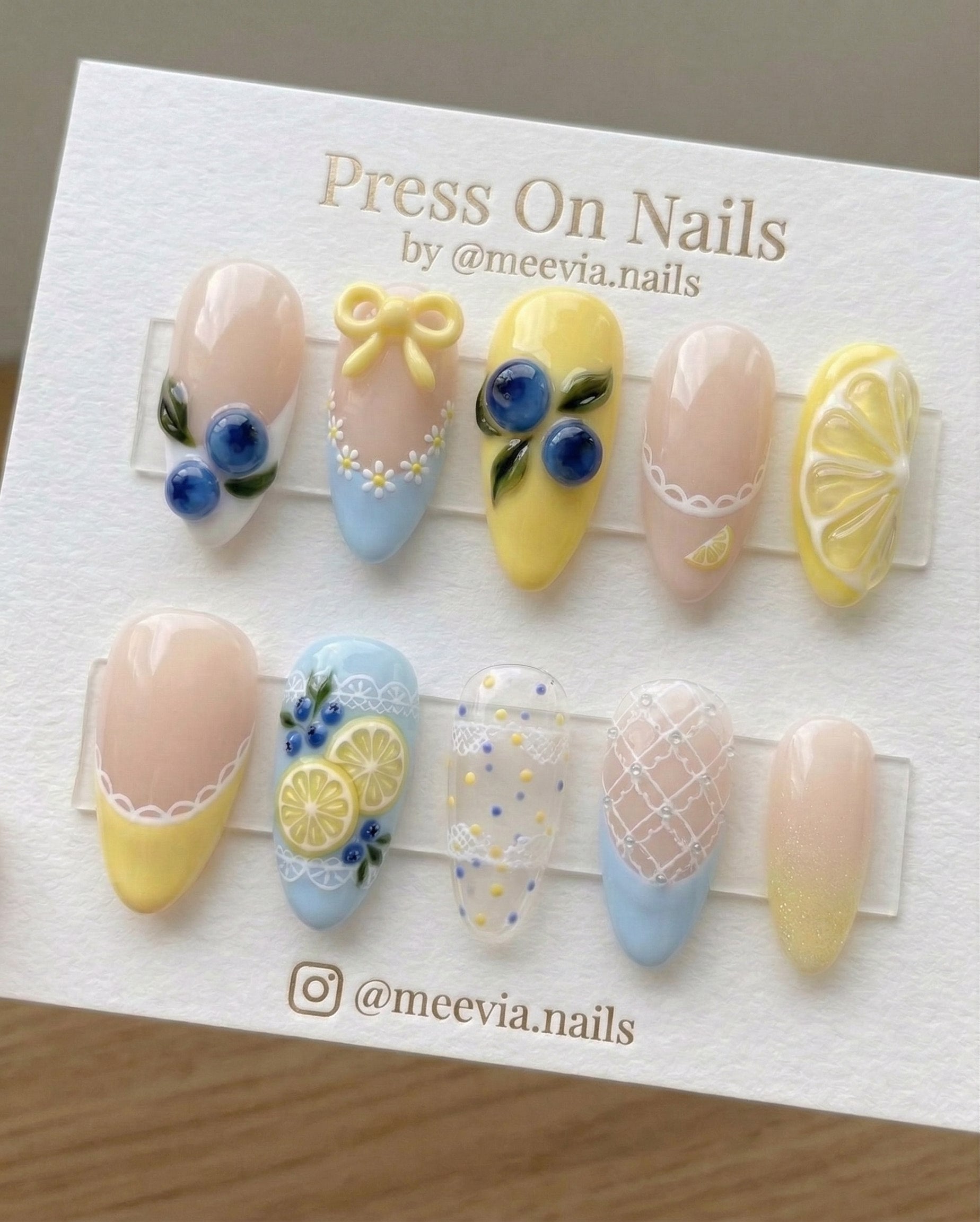 Almond-shaped press on nail set featuring 3D blueberry and lemon designs with yellow bows and lace art.