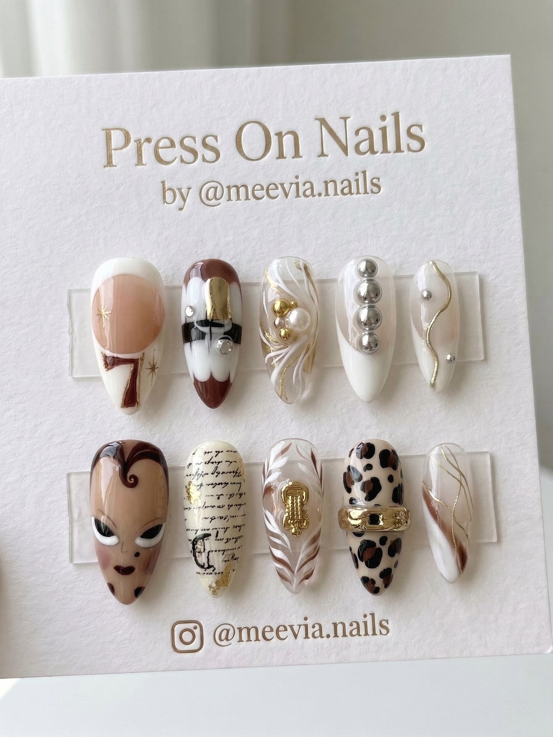 Stiletto-shaped eclectic press-on nails with mixed media designs including leopard print and 3D gold charms