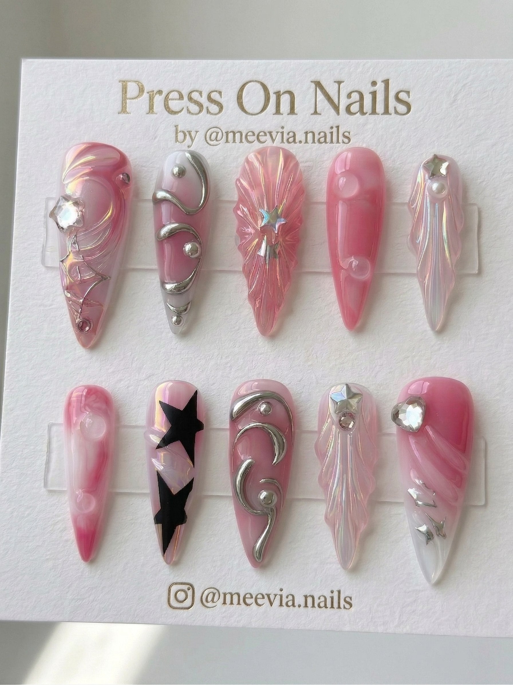 Long stiletto pink marble press-on nails with silver chrome 3D waves and black star motifs.