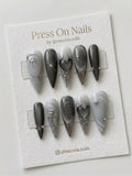 Stiletto-shaped grey and silver press-on nails with 3D chrome heart and starburst nail art