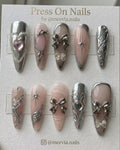 Long almond-shaped pink and silver chrome press-on nails with 3D bows and heart nail art