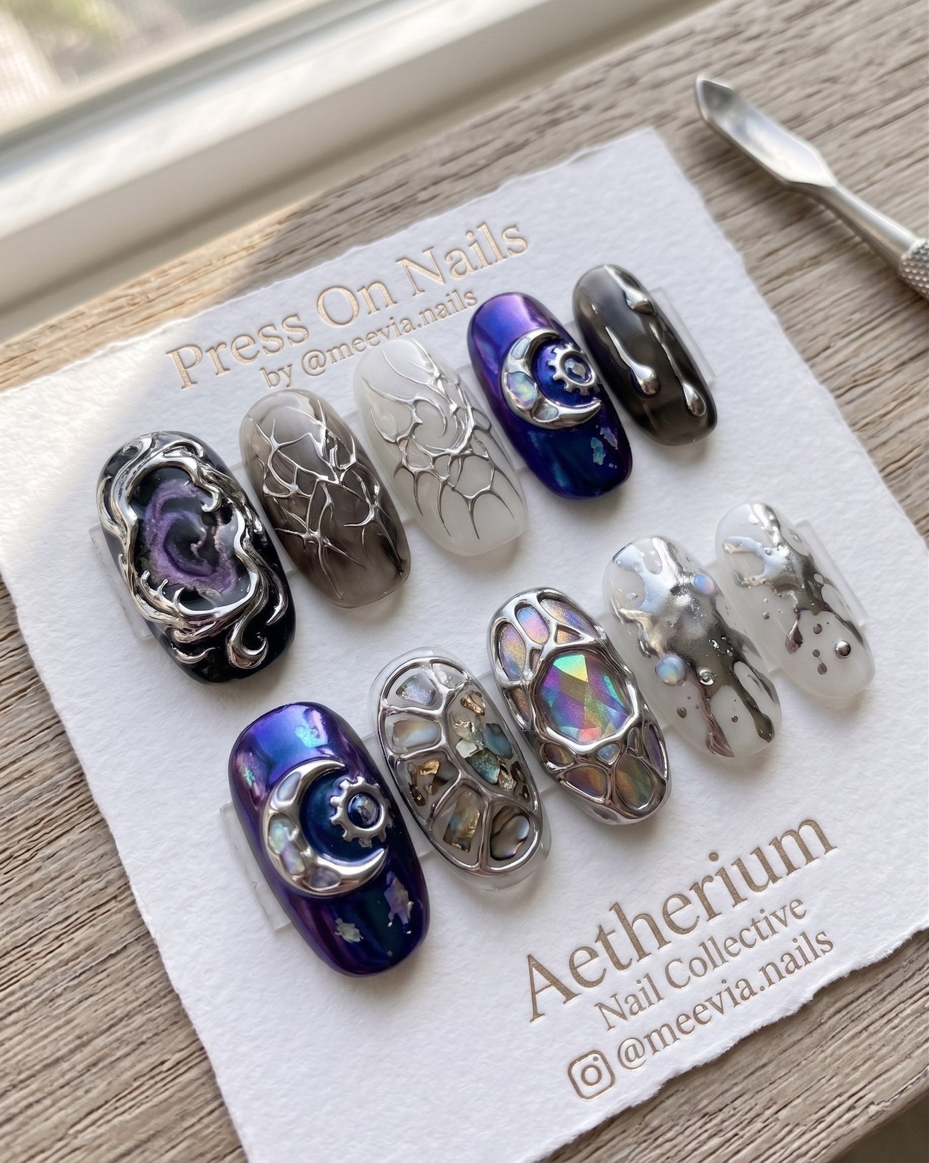 Stiletto-shaped silver chrome press-on nail set with 3D sculpted wing motifs