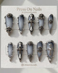 Stiletto-shaped gothic press on nails with smoky grey ombre and 3D silver chrome cross charms