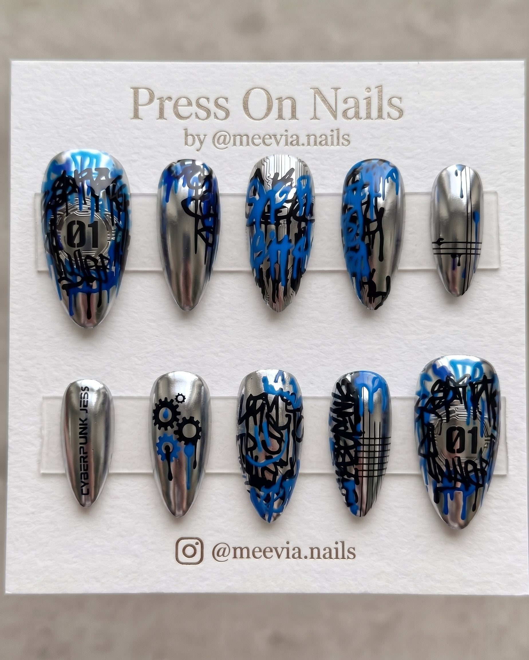 Almond-shaped iridescent chrome press-on nails with 3D silver thorns, hearts, and blue butterflies