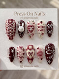 Stiletto-shaped black and white press-on nail set with 3D silver chrome accents and heart motifs.