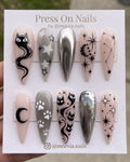Short rounded press on nails with blue starbursts, 3D silver chrome accents, and iridescent finishes.