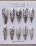 Stiletto-shaped milky white press on nails with 3D silver chrome swirls and metallic nail art