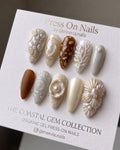 Almond-shaped press on nails with 3D coastal shell and coral art in pearl white and amber tones.