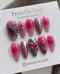 Almond-shaped pink ombre press-on nails with 3D silver butterflies and heart accents