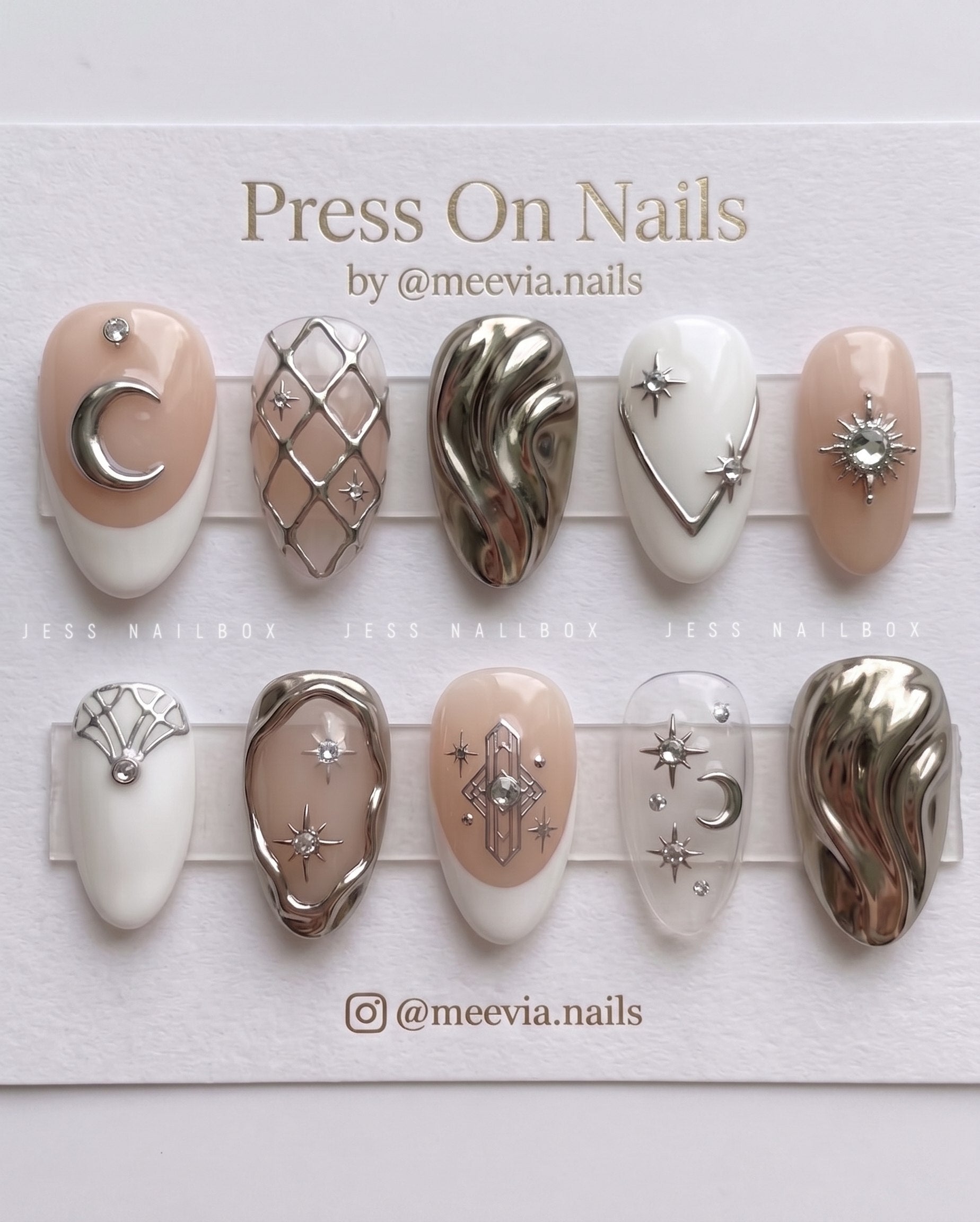 Almond-shaped press on nails featuring silver celestial motifs, 3D molten chrome, and nude French tips.
