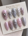 Almond-shaped pink shimmer press-on nail set with silver butterfly and bow 3D nail art.