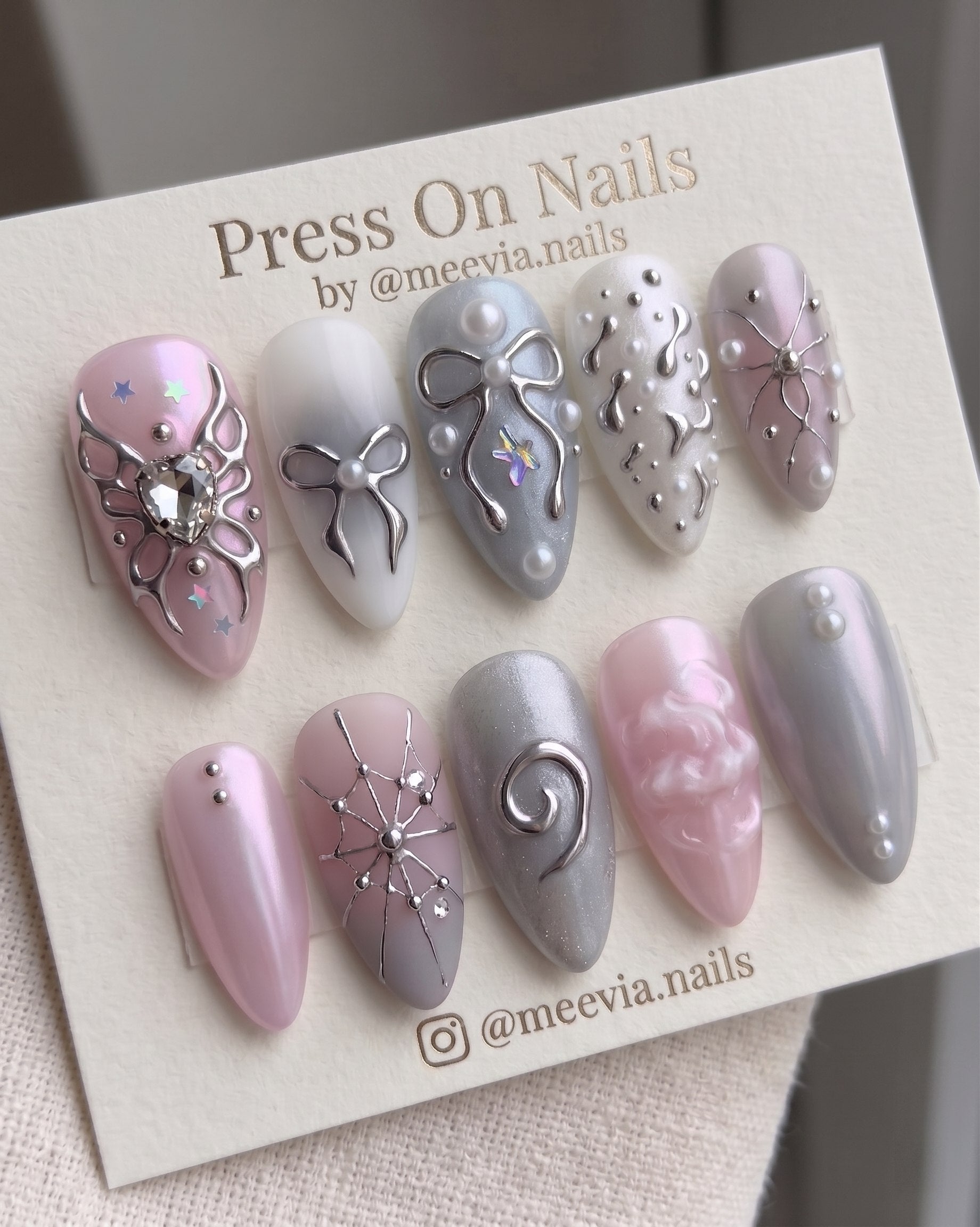 Almond-shaped pink shimmer press-on nail set with silver butterfly and bow 3D nail art.