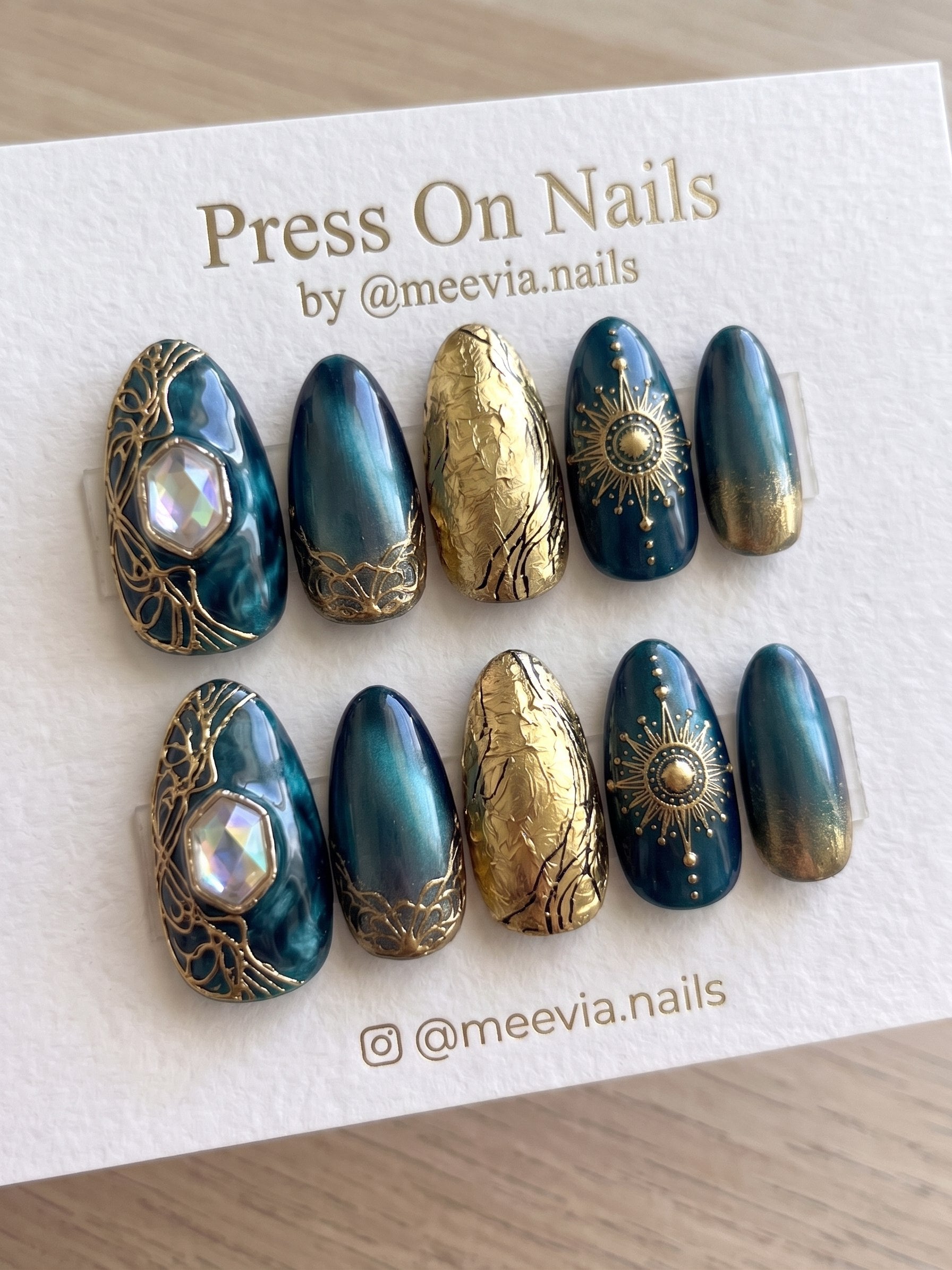 Almond-shaped teal and gold celestial press-on nail set with 3D sunburst and gemstone accents