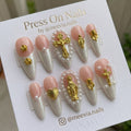 Long almond-shaped press on nails with pink and pearlescent white French tips, 3D gold crosses, and pearl accents.