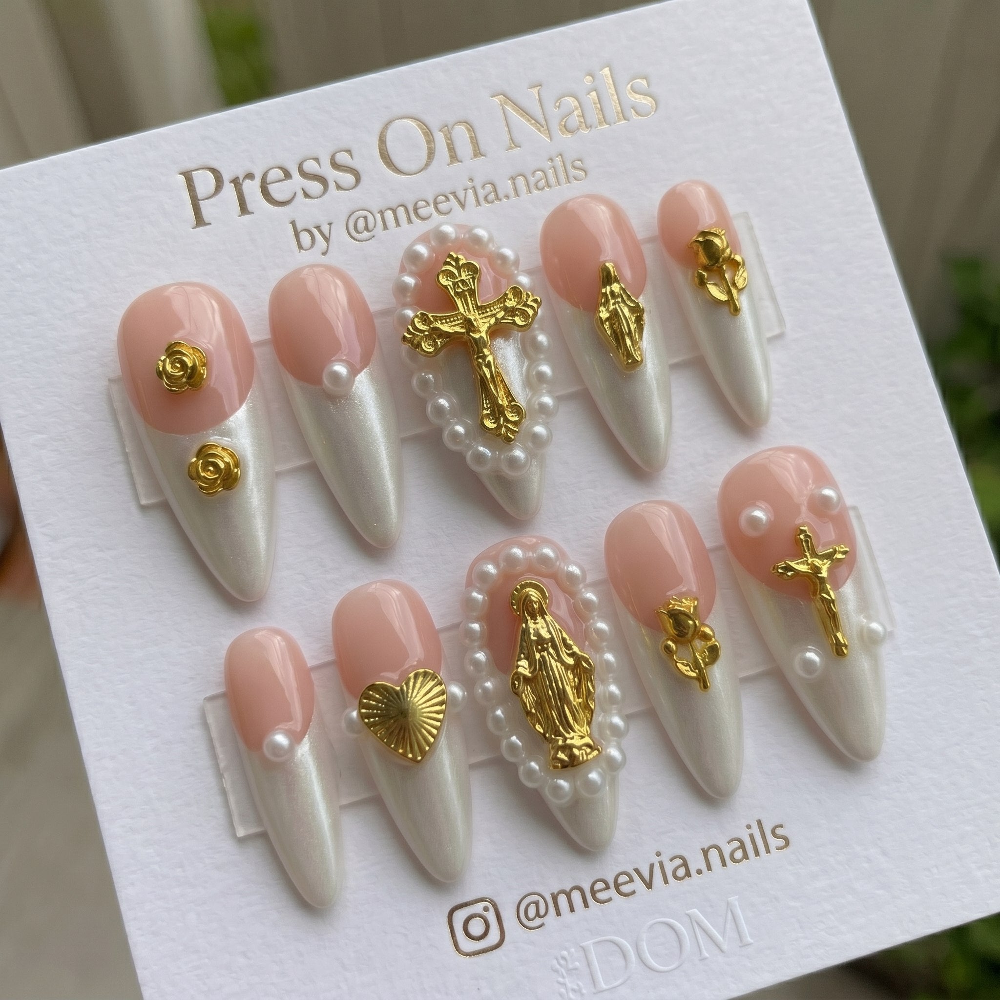 Long almond-shaped press on nails with pink and pearlescent white French tips, 3D gold crosses, and pearl accents.