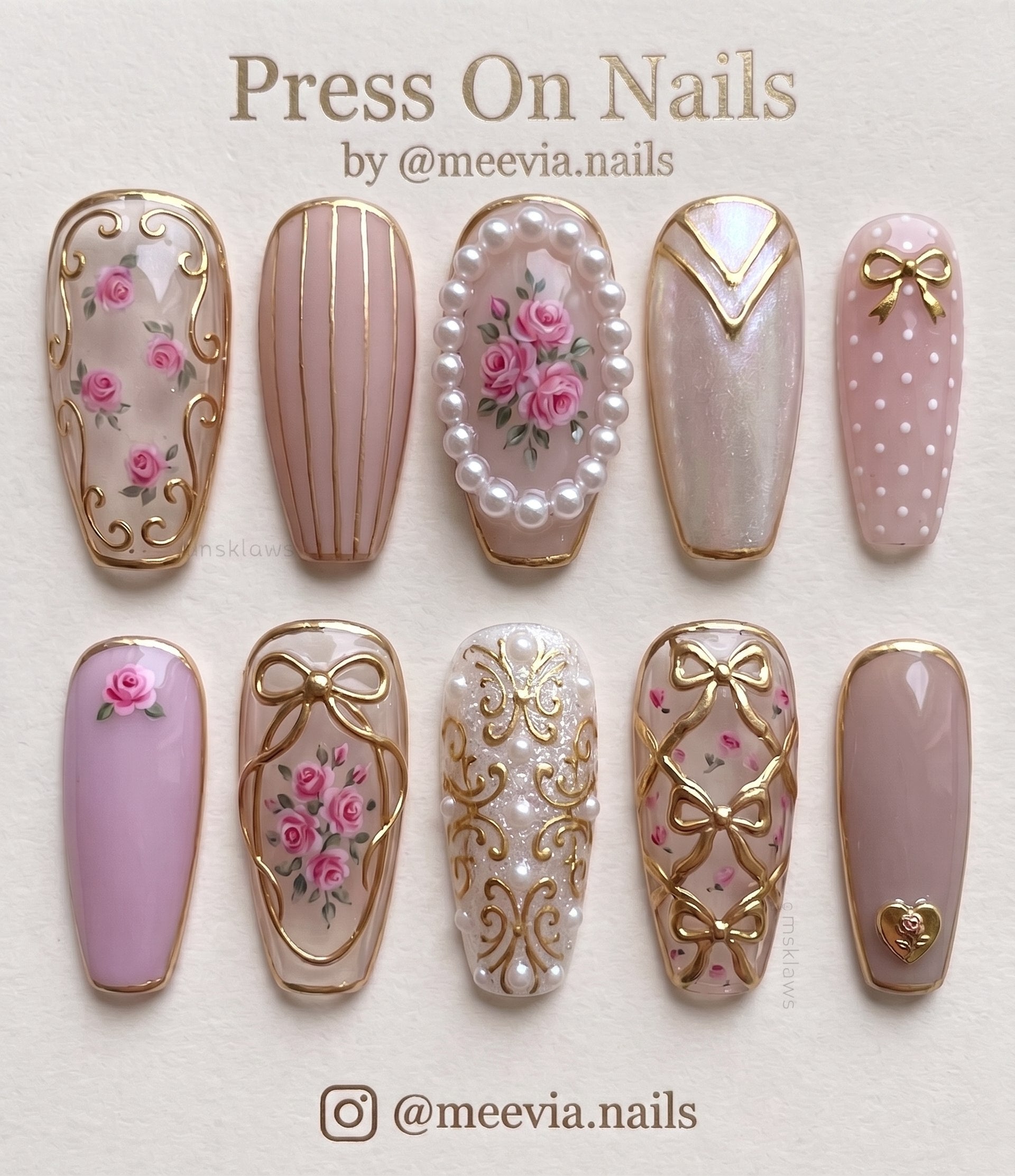 Coffin-shaped pink press-on nails with floral rose designs, gold bows, and 3D pearl embellishments.