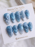 Almond-shaped blue cat eye press-on nails with 3D floral art and shimmering magnetic finish