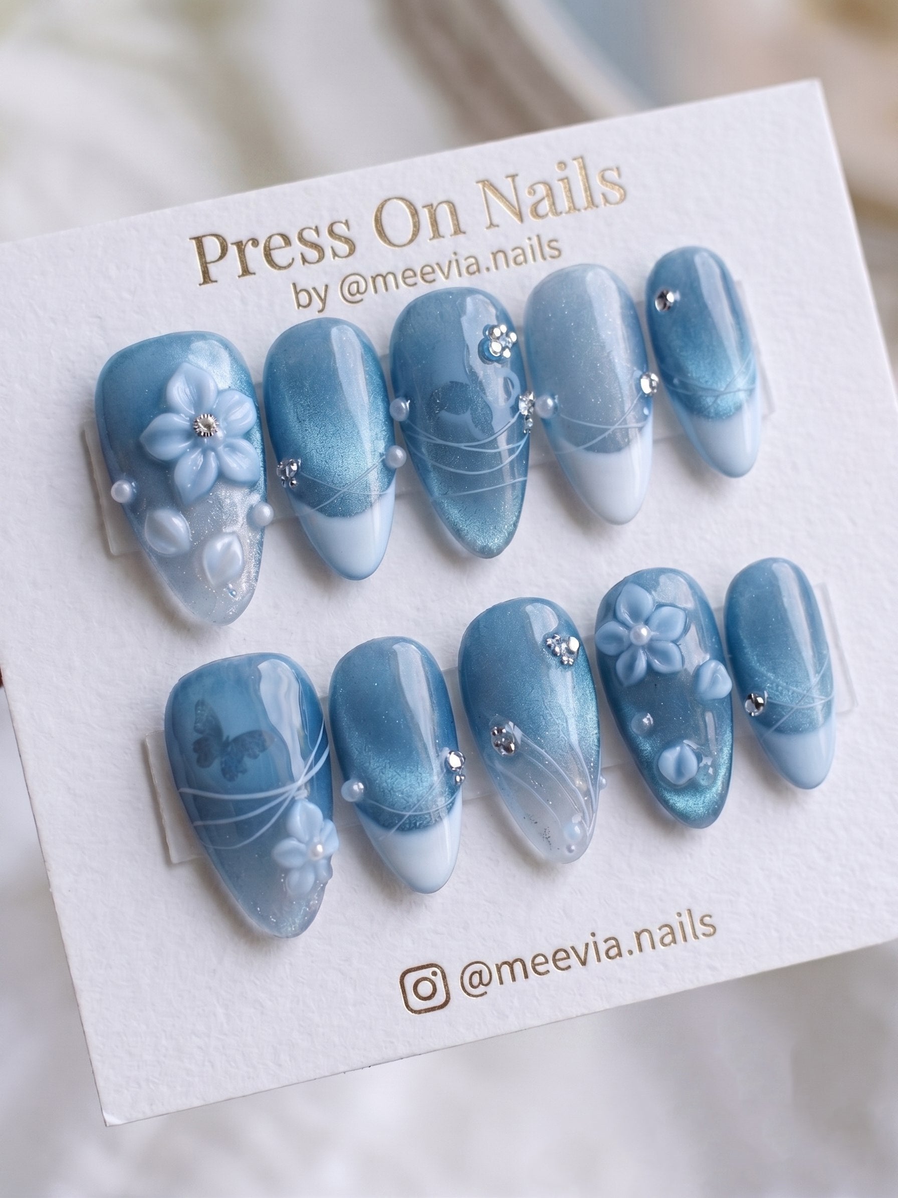 Almond-shaped blue cat eye press-on nails with 3D floral art and shimmering magnetic finish