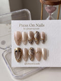 Almond-shaped gold tiger stripe press-on nail set with 3D accents and shimmer finish