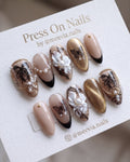 Almond-shaped nude and gold press-on nail set with 3D white flowers and butterfly motifs