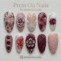 Almond-shaped burgundy and rose press-on nail set with 3D floral art, pearls, and water droplets.