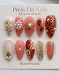 Almond-shaped press-on nail set with 3D floral designs, pearls, and gold filigree in red and pink.