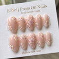 Almond-shaped nude press-on nails with cherry blossom floral motifs and 3D accents