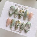 Almond-shaped sage green and cream press-on nail set with botanical leaf art and 3D pearl accents