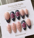 Almond-shaped press on nails with pink floral art and black dotted French tips